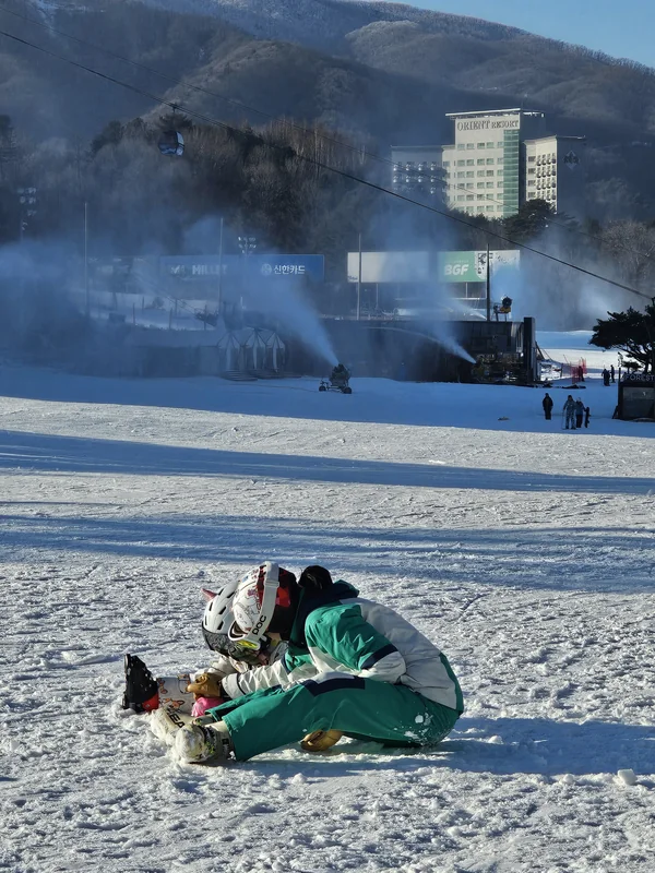 눈 위에 앉은 어린이 곁에서 자세를 낮춘 강사